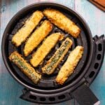an air fryer filled with breaded zucchini sticks
