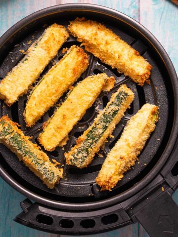 an air fryer filled with breaded zucchini sticks