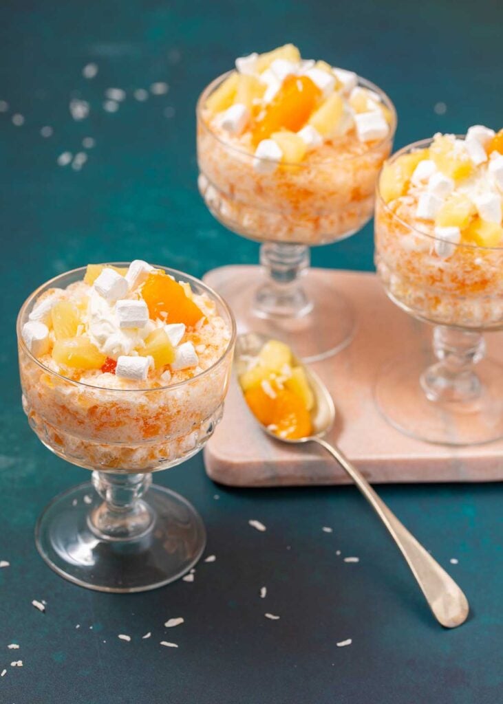 three bowls of salad with a spoon and some coconut strewn about